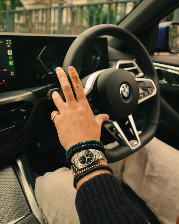 KKNEKKI Petrol. Man's hand with bracelets on a BMW steering wheel.  Kknekki's are for men too.