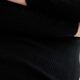 Detail of knit lightweight black ribbed sweater with sophisticated minimalist silhouette for effortless office, casual, and evening looks.