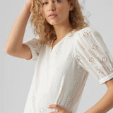 Feminine white broderie anglaise top featuring floral cutout embroidery and relaxed silhouette.