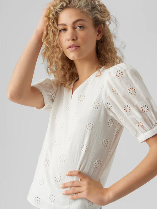 Feminine white broderie anglaise top featuring floral cutout embroidery and relaxed silhouette.