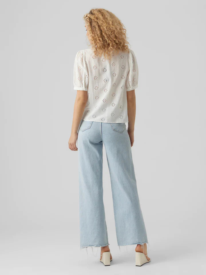Feminine white broderie anglaise top with puff sleeves and floral embroidery accents.