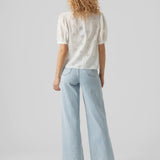 Feminine white broderie anglaise top with puff sleeves and floral embroidery accents.