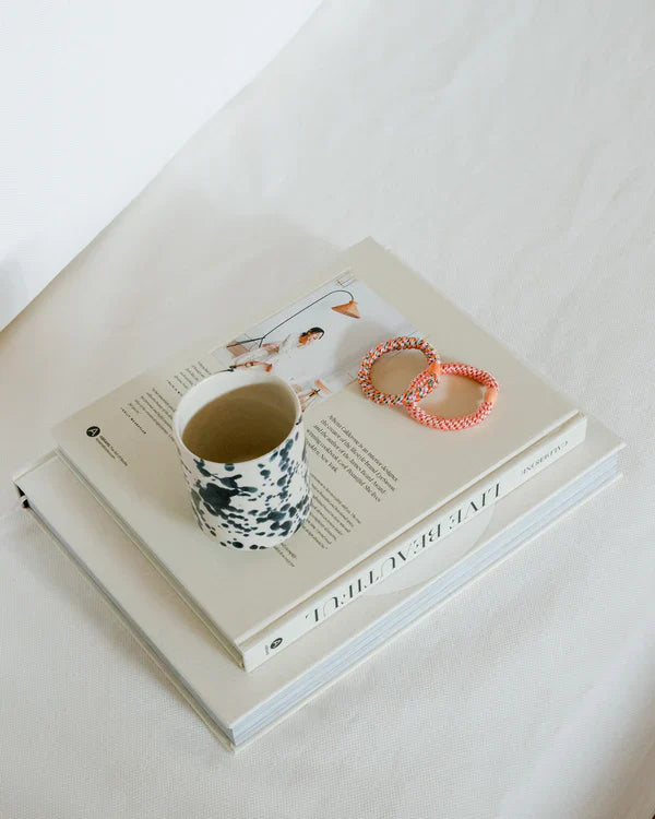 KKNEKKI Mix Orange Pistachio Glitter, big, bold and colorful. A cup of tea and two books, with an orange and multi-colored Kknekki hair ties.