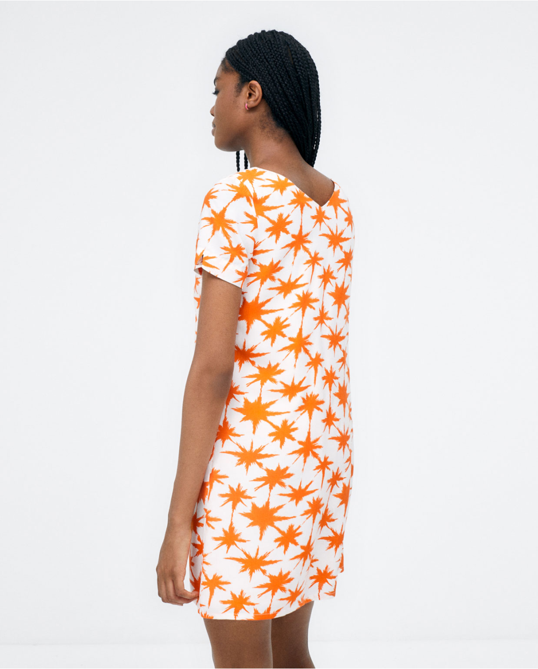 Women's orange starburst print mini dress with relaxed fit and V-neck design.