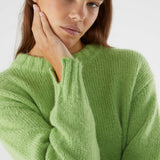 Minimalist oversized knit sweater with soft fuzzy fabric and modern relaxed fit in trendy pastel green shade.