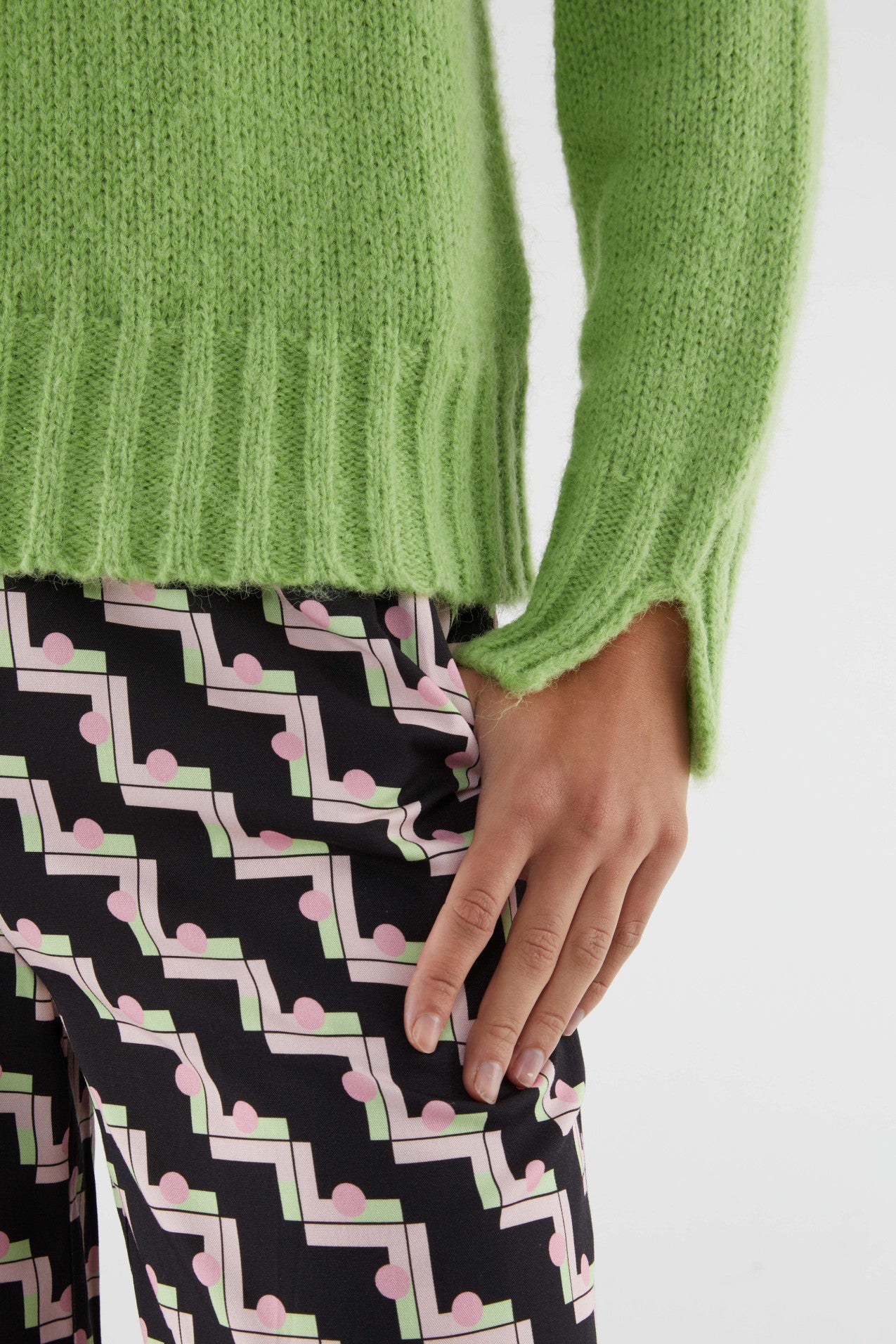 Detail of knit, ribbed slit cuff of chic pastel green knitted sweater featuring relaxed fit, long sleeves, and cozy textured fabric for stylish layering.