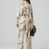 Women’s luxury-inspired cream blouse with flowing black abstract pattern and silky button-up construction for elegant fashion outfits.