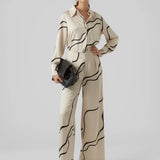 Modern cream satin blouse with bold abstract stripes and collared neckline for elevated everyday women’s fashion.
