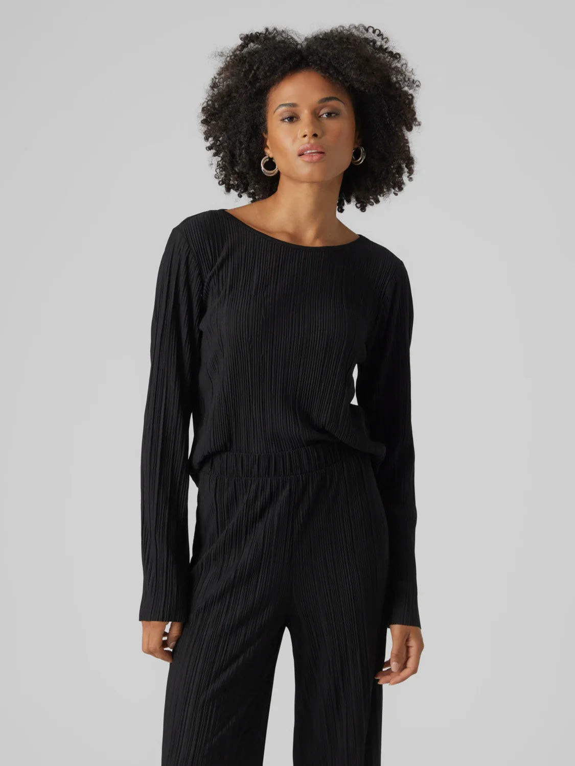 Women’s minimalist black textured blouse with elegant pleats and modern effortless chic styling.