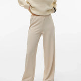 Women's light beige wide-leg pants featuring a relaxed draped fit and minimalist design for an elevated capsule wardrobe.