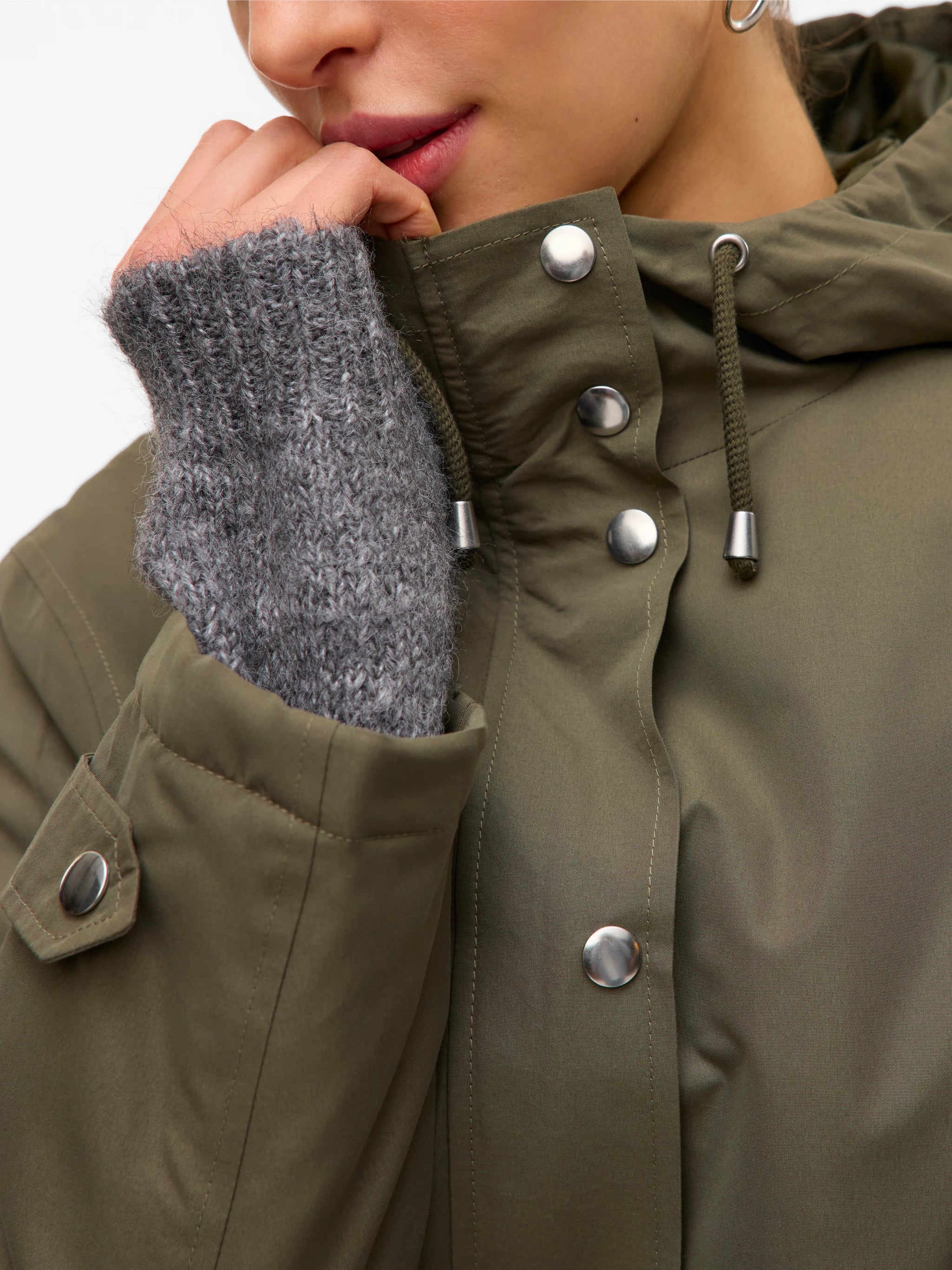 Detail of silver buttons and drewstring hood of this chic weather-resistant women’s jacket with minimalist silhouette and elevated off-duty fashion.