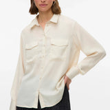 Women’s ivory button-down shirt with long sleeves, chest pockets, and relaxed fit for office, casual and smart casual outfits.