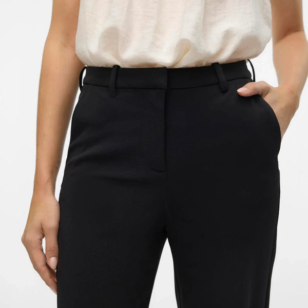 Women’s high-waisted black trousers with wide leg design and timeless professional chic fashion look.