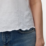Minimalist white crew neck top featuring delicate tonal floral embroidery, lightweight fabric and modern relaxed silhouette for boutique fashion.