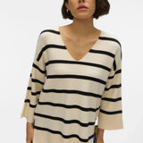 Oversized cream knit sweater with bold black stripes and relaxed silhouette for timeless chic streetwear-inspired style.