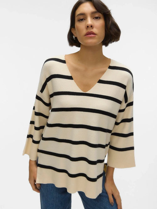 Oversized cream knit sweater with bold black stripes and relaxed silhouette for timeless chic streetwear-inspired style.