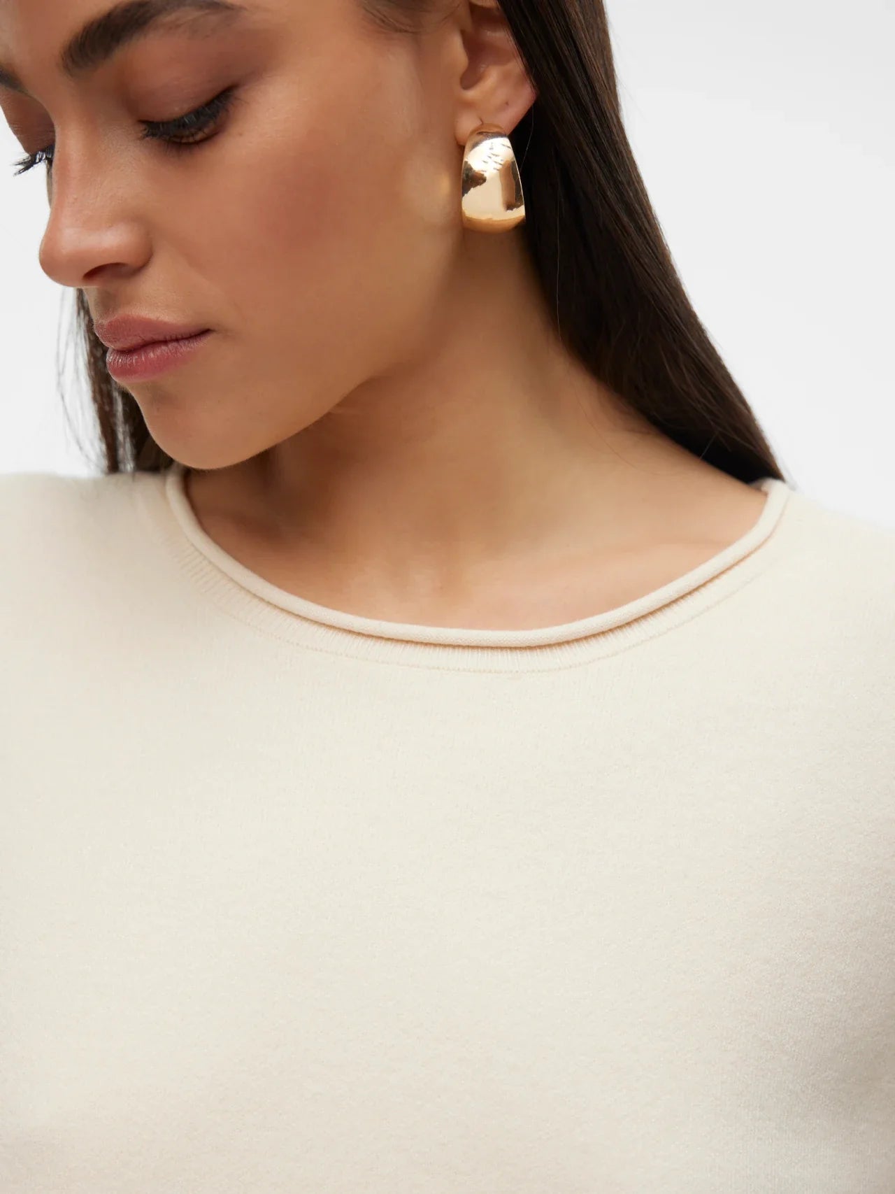 Detail of rolled neck of contemporary women’s beige knit top with understated luxury aesthetic and easy everyday layering style.