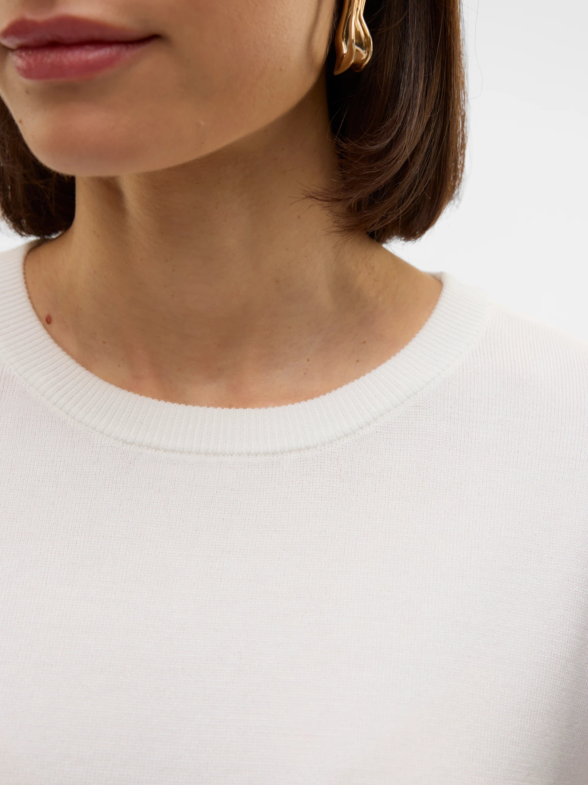 Women's elegant ivory crew neck sweater top with fine knit texture and short cuffed sleeves for capsule wardrobes, travel and everyday layering.